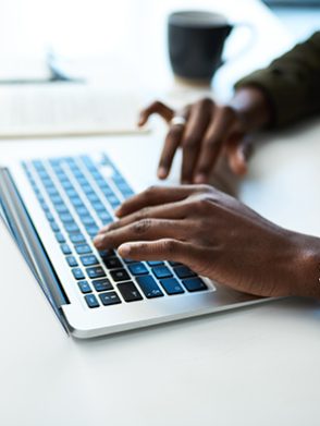 Cropped shot of an unrecognisable businessman using a laptop at his desk in a modern office