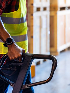 Close up of african black warehouse worker hand hold hand pallet jack in distribution warehouse with copyspace. Business warehouse and logistic concept.