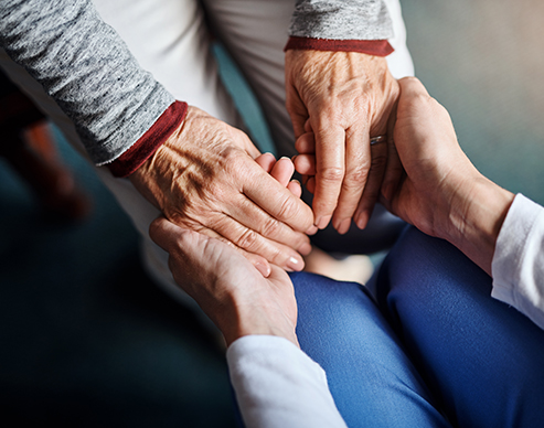 Cropped shot of a nurse holding a senior woman’s hands in a retirement home
