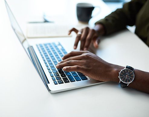 Cropped shot of an unrecognisable businessman using a laptop at his desk in a modern office