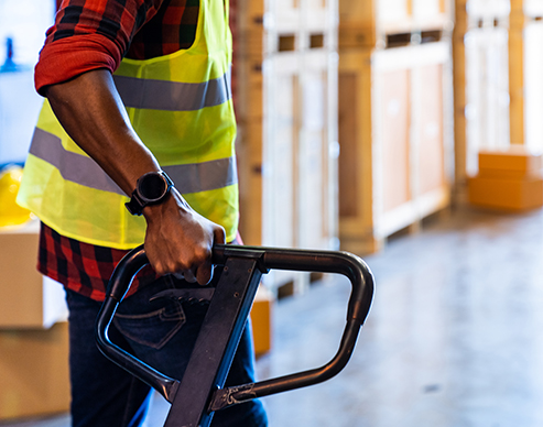 Close up of african black warehouse worker hand hold hand pallet jack in distribution warehouse with copyspace. Business warehouse and logistic concept.